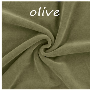 Op de afbeelding: Een stuk olijfgroene stof met een zachte, fluweelachtige textuur. Het materiaal is gedrapeerd in een wervelend patroon, waardoor diepe plooien en schaduwen op het oppervlak ontstaan. Het woord "olive" staat in witte letters bovenaan.