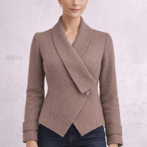 May include: A taupe-colored jacket with a unique asymmetrical design. The jacket features a wide, draped collar and a silver-toned clasp. The sleeves have a cuff detail. The textured fabric adds visual interest to this stylish outerwear.