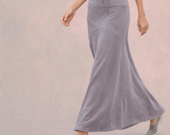 Op de afbeelding: Een enkellange maxi-rok in een stoffige paarse kleur met een hoge taille en een trekkoord. De rok heeft een nauwsluitend bovenstuk met een gebogen naad die overgaat in een wijd uitlopende, vloeiende zoom, gemaakt van een zachte stof.