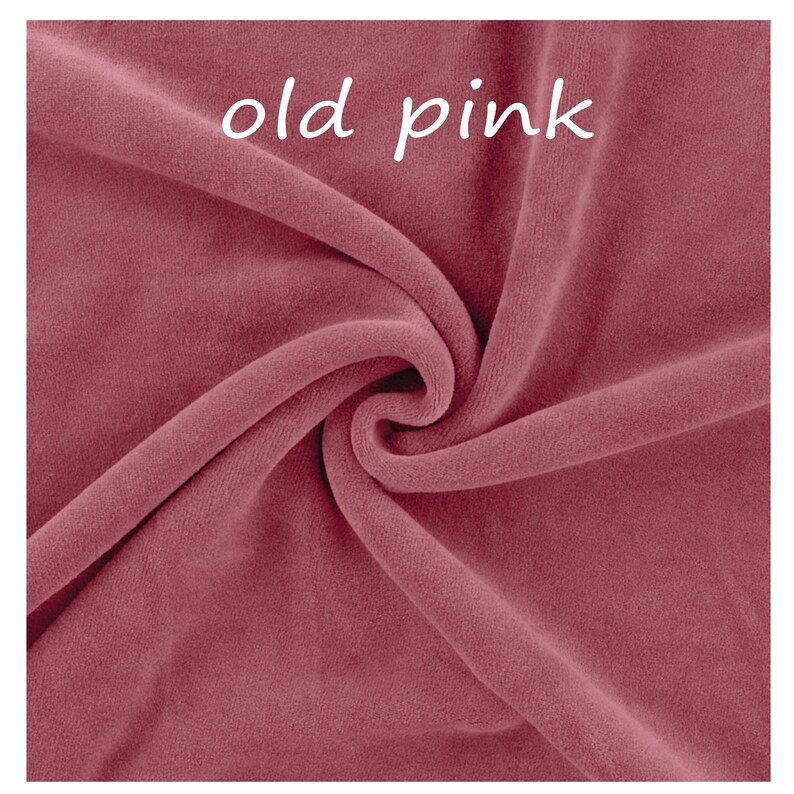 Op de afbeelding: Een stuk stof in oudroze kleur met een zachte, fluweelachtige textuur. Het materiaal is in plooien gedrapeerd, waardoor schaduwen en highlights op het oppervlak ontstaan. De tekst "old pink" staat in het wit in het midden bovenaan de afbeelding.