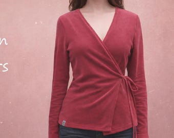 Op de afbeelding: Een wikkelshirt met lange mouwen in een dieprode kleur, voorzien van een V-hals en een striksluiting aan de zijkant. Het kledingstuk is gemaakt van een zacht aanvoelende stof en heeft een klein rechthoekig label bij de onderzoom.