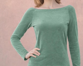 Op de afbeelding: Een top met lange mouwen in een gedempte saliegroene kleur, voorzien van een brede boothals en een zachte, getextureerde afwerking. Het kledingstuk heeft een aansluitend silhouet met raglanmouwen en een rechte zoom op de taille.