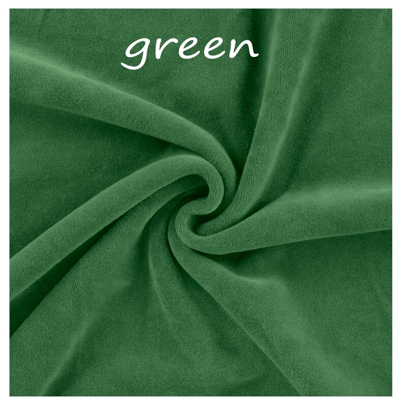 Op de afbeelding: Een effen donkergroene stof met een zachte, fluweelachtige textuur met plooien en rimpelingen die diepte cre&euml;ren. Het woord green is gedrukt in witte, kleine, schreefloze letters nabij het bovenste midden van het textieloppervlak.