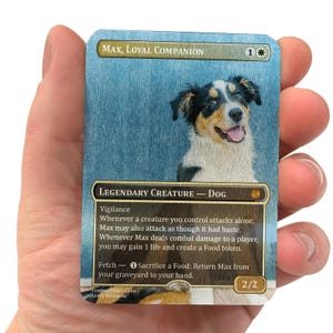 May include: A rectangular trading card featuring a portrait of a tricolor dog with black, white, and tan fur. The card is titled Max, Loyal Companion and includes game text describing abilities, a 2/2 power and toughness, and a cost of 1 white mana.