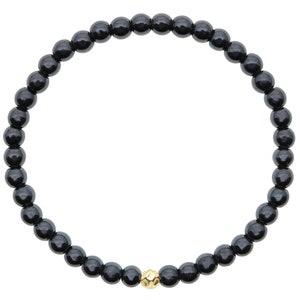 May include: A black beaded bracelet with a single gold bead.