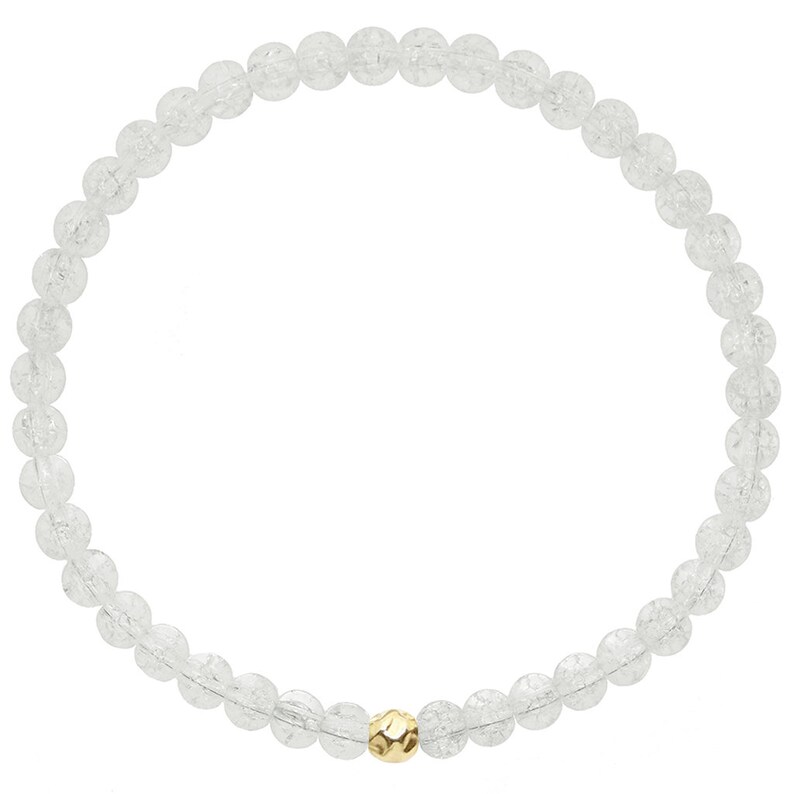 May include: A white crystal beaded bracelet with a gold bead accent. The bracelet is made of small, round beads and is strung on a clear elastic cord.