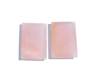 May include: Two rectangular pink agate cabochons with a smooth, polished surface. The cabochons are translucent and have a light pink colour with white streaks.