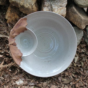 May include: White ceramic serving dish with a smaller bowl attached. The dish has a leaf design on the side.