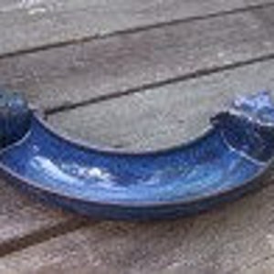 May include: A black rubber car part with a curved shape and two small holes on each side.