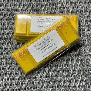 May include: Two yellow wax melts in clear packaging. The wax melts are labelled "Four Wicks Handmade Soy Candles" and "Banana Paddle Pop".
