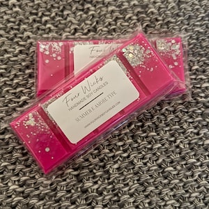 May include: Two pink wax melts with silver glitter, packaged in clear plastic. The wax melts are labelled "Four Wicks Handmade Soy Candles" and "Summer E Amore Type".