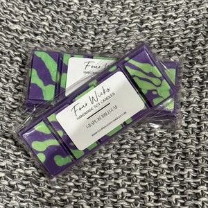 May include: A wax melt set with a purple and green swirl design. The label reads "Four Wicks Handmade Soy Candles Grape Bubblegum www.fourwickssoyscandles.com".