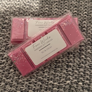 May include: Pink wax melt with glitter, labelled "Four Wicks Handmade Soy Candles" and "Musa Sticks" with the website address "www.fourwickssoycandles.com".