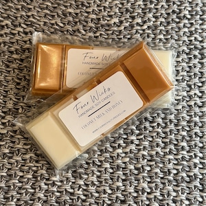 May include: Two packages of soy wax melts, one with a gold wax melt and the other with a white wax melt. The labels on both packages read "Four Wicks Handmade Soy Candles" and include the scent names "Coconut Milk and Honey" and "Coconut".
