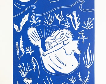 May include: A blue and white linocut print featuring a mermaid swimming underwater among various sea plants and coral. Above the water line, a large white moon shines in the blue sky, accompanied by small stars and a wavy horizon line.