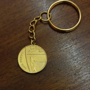 May include: A gold-colored keychain with a one penny coin attached. The coin features a harp and the words "ONE PENNY".