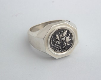 May include: A silver ring with an octagonal face featuring a detailed engraving of a woman's head in profile, wearing a helmet.