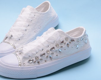 May include: White lace sneakers with a white rubber sole and a row of rhinestones on the side.
