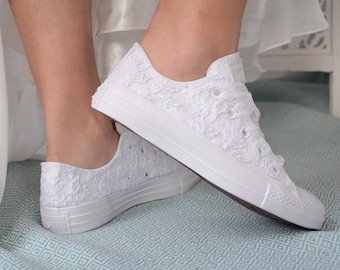 Könnte beinhalten: Weiße Converse-Sneaker mit weißen Schnürsenkeln aus Spitze. Die Sneaker werden von einer Person getragen, die ein weißes Kleid trägt.