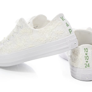 May include: White lace Converse sneakers with green embroidery. The left shoe has "K & P" embroidered on the back, and the right shoe has "10 &hearts; 10 &hearts; 24" embroidered on the back.