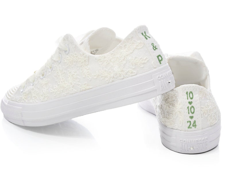 May include: White lace Converse sneakers with green embroidery. The left shoe has "K & P" embroidered on the back, and the right shoe has "10 &hearts; 10 &hearts; 24" embroidered on the back.