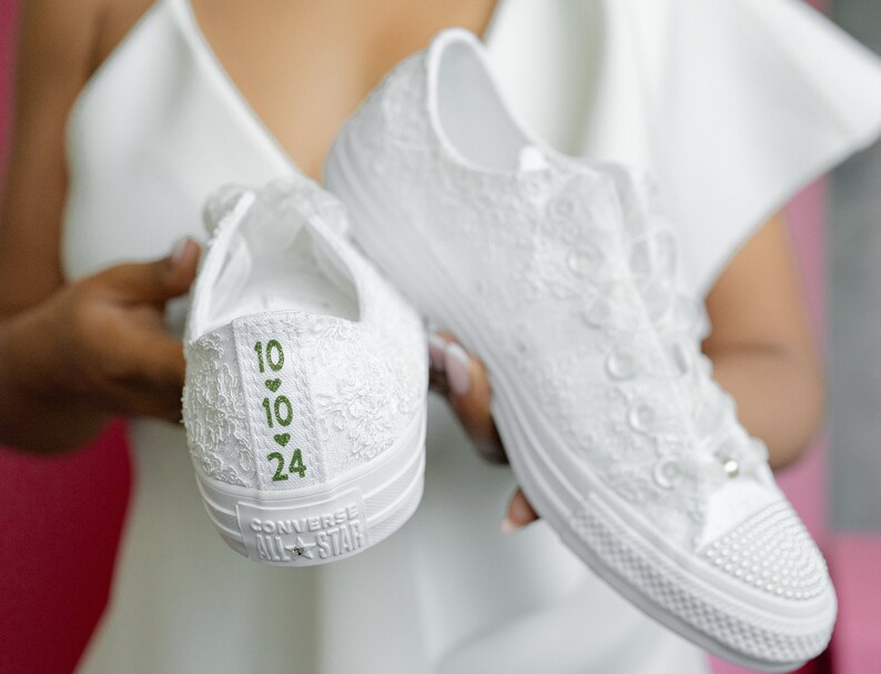 May include: White lace Converse All Star trainers with green numbers and hearts on the back. The numbers are 10, 10, and 24.