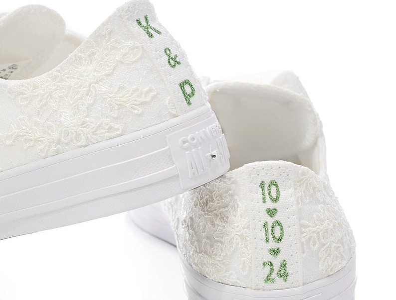 May include: White lace Converse sneakers with green embroidery. The left shoe has "K & P" embroidered on the back, and the right shoe has "10 &hearts; 10 &hearts; 24" embroidered on the back.
