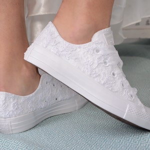 Elegant lace-adorned white Converse for brides. Customizable low-top tennis shoes with Dubai lace. Perfect for a luxurious wedding, adding style and comfort to the bride's special day