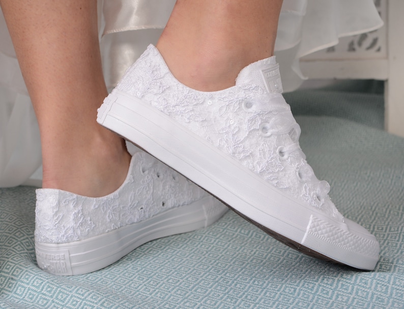 Elegant lace-adorned white Converse for brides. Customizable low-top tennis shoes with Dubai lace. Perfect for a luxurious wedding, adding style and comfort to the bride's special day
