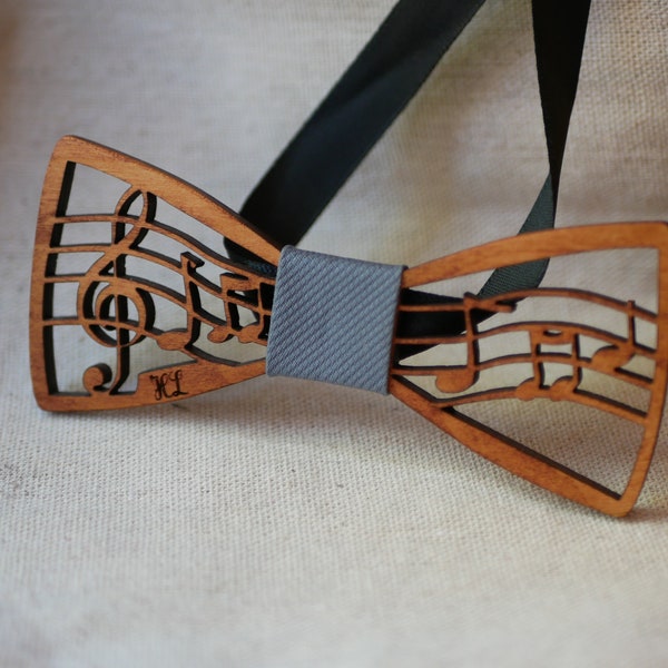 Music wood bow tie, musical notes and treble clef on a wooden partition, for a musical wedding or a musician