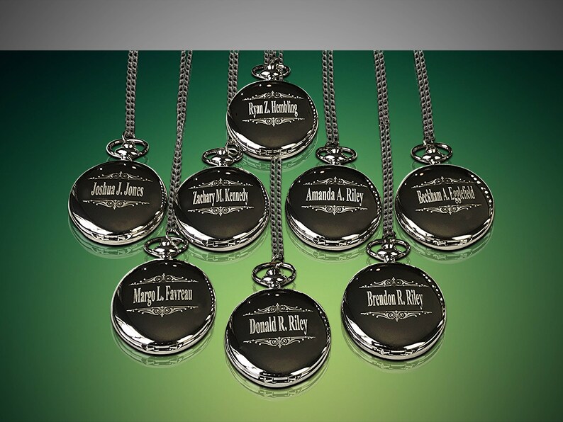 Puede incluir: Ocho relojes de bolsillo plateados con cadenas que cuelgan de un fondo verde. Cada reloj tiene un nombre diferente grabado en la parte delantera.