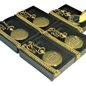 Puede incluir: Cinco relojes de bolsillo dorados con cadenas en cajas negras. Cada reloj tiene una inscripci&oacute;n personalizada con el t&iacute;tulo "Groomsman" y una fecha.