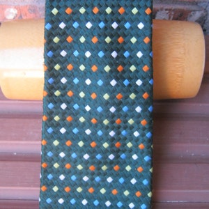 May include: A dark green tie with a repeating pattern of small white, orange, light green, and blue squares.