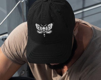 May include: A black baseball cap with a white embroidered moth design. The moth has a skull and crossbones on its body.