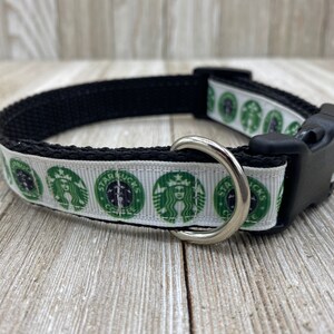May include: A white and green dog collar with a repeating pattern of the Starbucks logo. The collar has a black adjustable buckle and a silver D-ring.