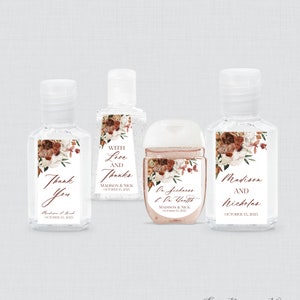 May include: Four clear hand sanitizer bottles with white labels and floral designs. The labels include text such as "Thank You", "With Love and Thanks", and names with a date. The bottles have clear caps.