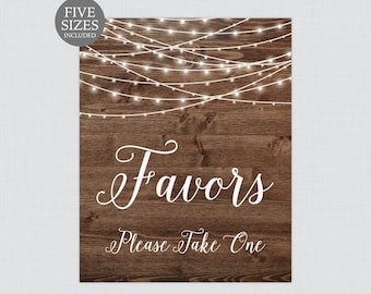 May include: A rustic wooden sign with string lights and the text "Favors Please Take One" in white script font. The sign is decorated with a brown wood grain background and white string lights. The text "The Papered Wedding" is in a smaller font at the bottom of the sign.