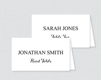 May include: Two white place cards with black text. The top card reads "SARAH JONES Table Two". The bottom card reads "JONATHAN SMITH Head Table".