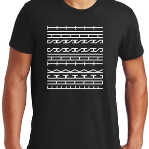 May include: Black t-shirt featuring a white geometric design. The design consists of horizontal lines, zigzags, and rectangular shapes. The shirt is made of a soft material and has short sleeves.