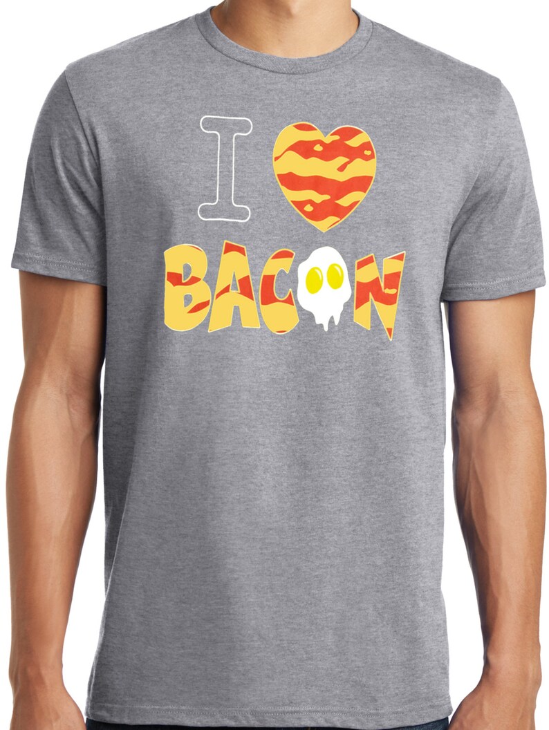 Puede incluir: Camiseta gris con el texto "Me encanta el bacon" en una fuente estilizada. La palabra "bacon" est&aacute; compuesta por tiras de tocino y un huevo frito.