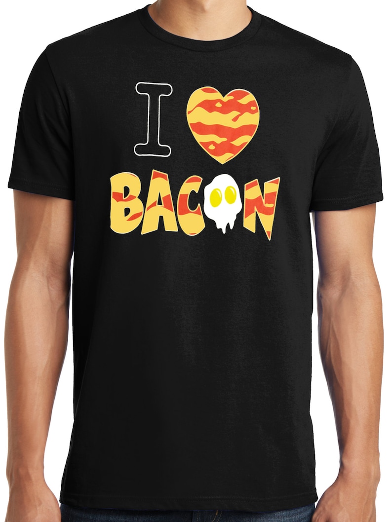 Puede incluir: Camiseta negra con el texto "I love bacon" en letras amarillas y naranjas. Un gr&aacute;fico en forma de coraz&oacute;n con un patr&oacute;n de tocino est&aacute; por encima del texto. Un gr&aacute;fico de huevo est&aacute; dentro de la palabra "bacon".
