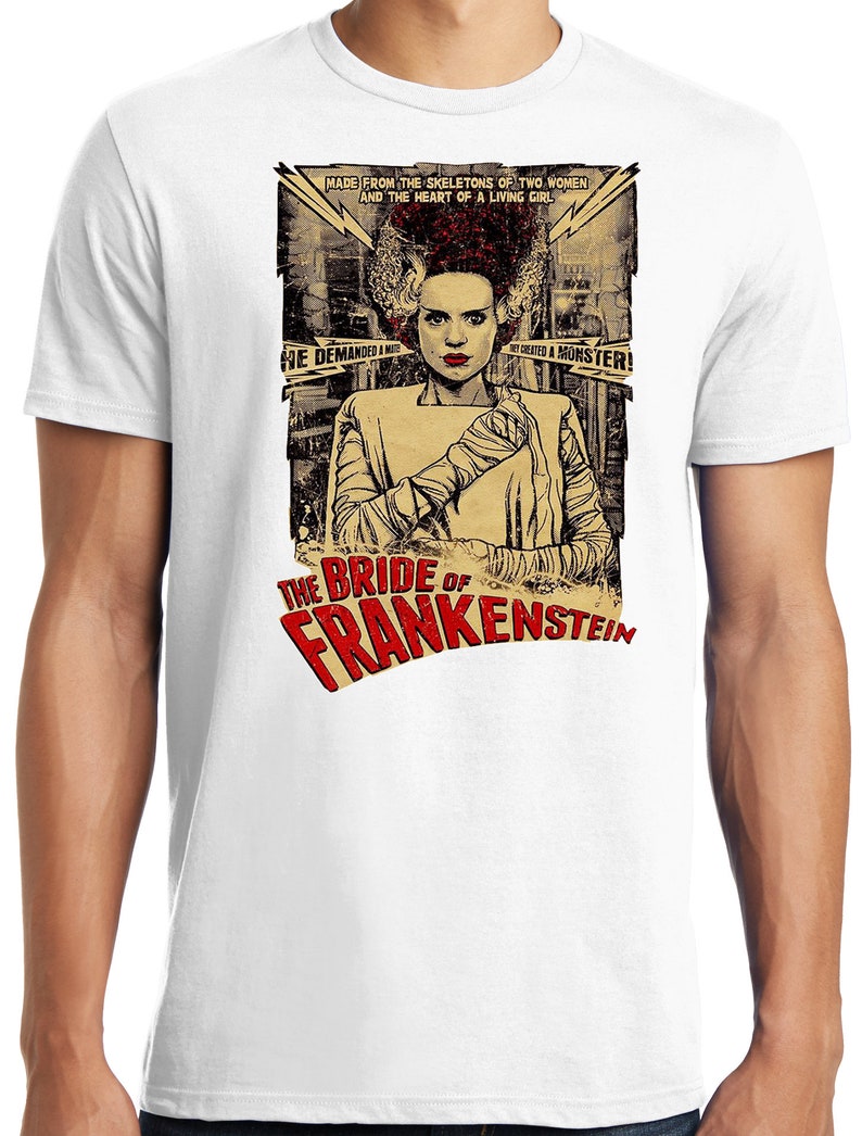 Puede incluir: Una camiseta blanca con un gr&aacute;fico de estilo vintage de la Novia de Frankenstein. El gr&aacute;fico presenta a una mujer con cabello verde y puntadas, vistiendo un vestido blanco y vendas. El texto "The Bride of Frankenstein" est&aacute; en letras rojas y blancas.