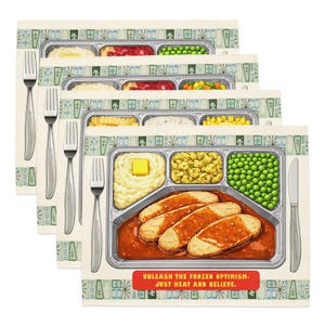 May include: Four placemats with a vintage TV dinner design. Each mat shows a tray with compartments of food like mashed potato, peas, and meat. The text "UNLEASH THE FROZEN OPTIMISM - JUST HEAT AND BELIEVE" is printed on the bottom. Includes forks and a knife.