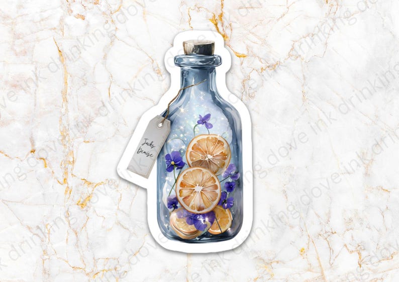 Op de afbeelding: Een blauwe glazen fles met een kurkstop, gevuld met gedroogde sinaasappelschijfjes en paarse bloemen. De fles heeft een etiket met de tekst "Jacky Denise".