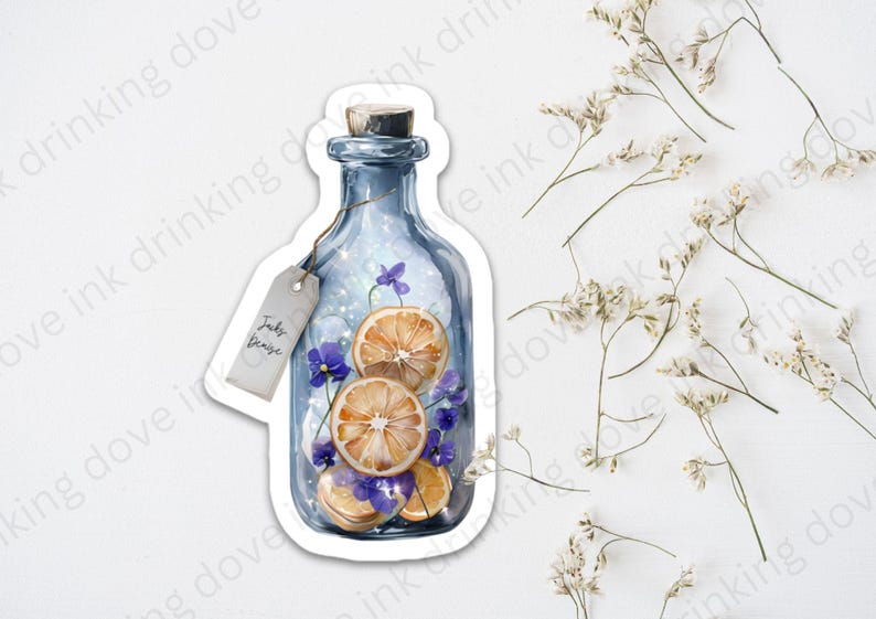 Op de afbeelding: Een blauwe glazen fles met een kurkstop, gevuld met gedroogde sinaasappelschijfjes en paarse bloemen. De fles heeft een label met de tekst "Jacky Genie".