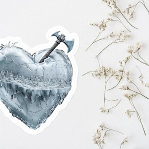May include: A silver heart-shaped sculpture with a small axe piercing through it. The heart is cracked and appears to be melting, with water dripping from the edges.