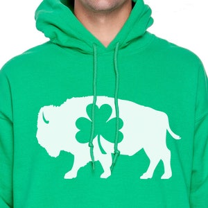 May include: A green hooded sweatshirt with a white silhouette of a buffalo with a shamrock on its back.
