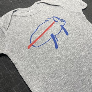 May include: A gray baby onesie featuring a blue and red graphic design. The design appears to be a stylized animal or creature. The onesie is made of soft fabric and has short sleeves.