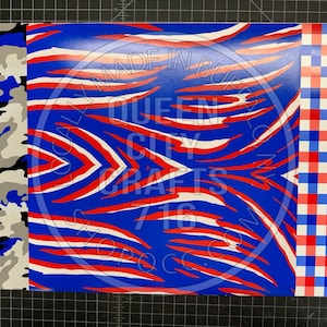 May include: Red, white, and blue patterned fabric with a zebra stripe design. The fabric is bordered on the left with a blue, black, and gray camouflage pattern and on the right with a red and blue gingham pattern. The fabric has the text "Locally Made in Buffalo, Queen City Crafts 716 ShopQCC.com" printed on it.