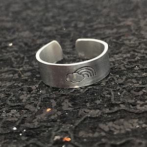 May include: A silver adjustable ring with a cloud and rainbow design.